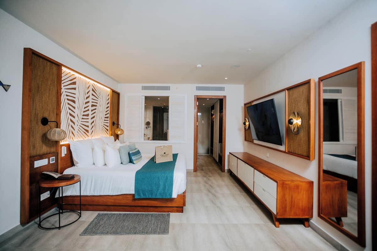 A modern bedroom with a bed, bedside table, TV, and wardrobe.