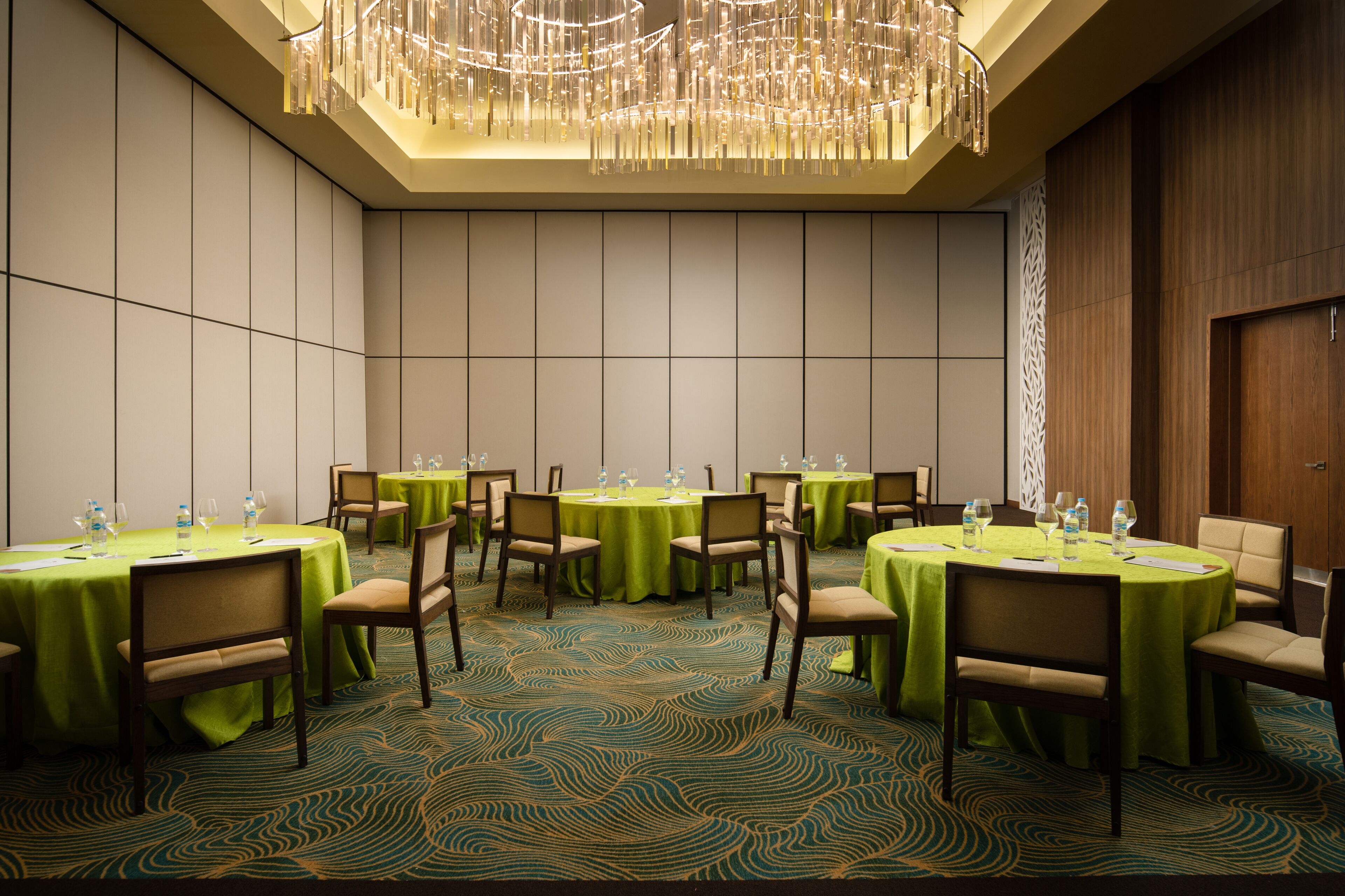 A conference room with round tables, chairs, and a chandelier.