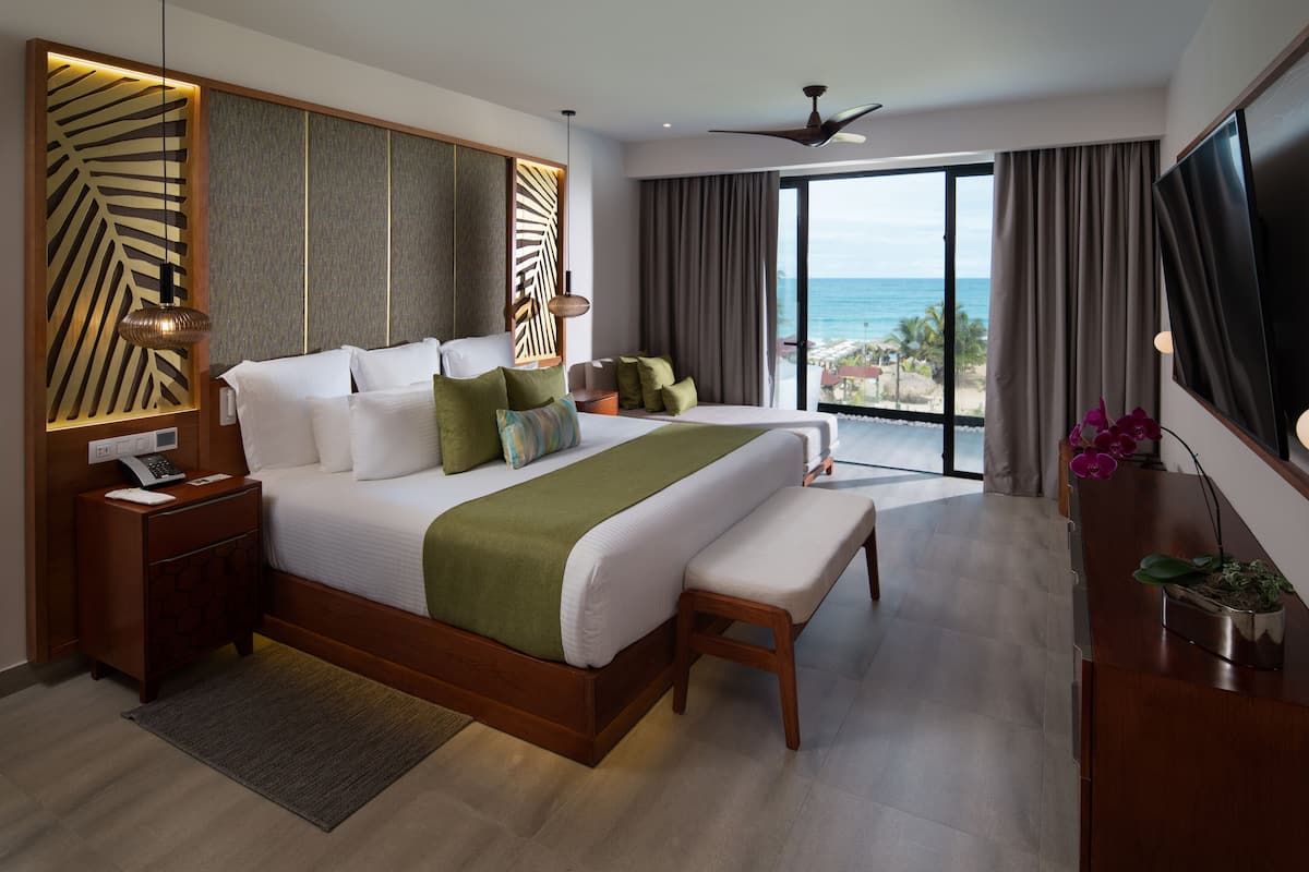 A modern hotel room with a large bed, a bench, a desk, and a TV.