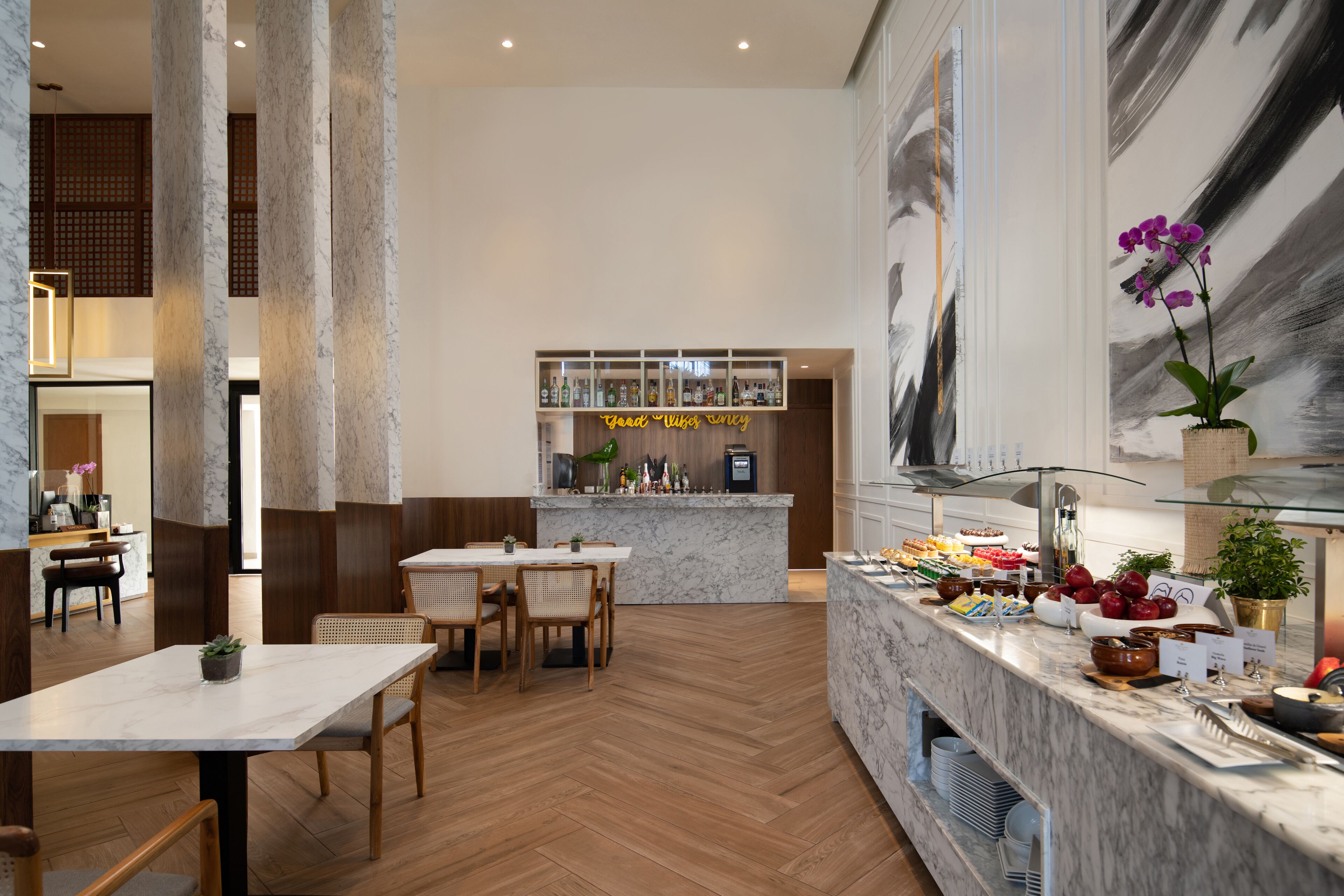 A modern restaurant with marble countertops, wooden flooring, and a central bar area.