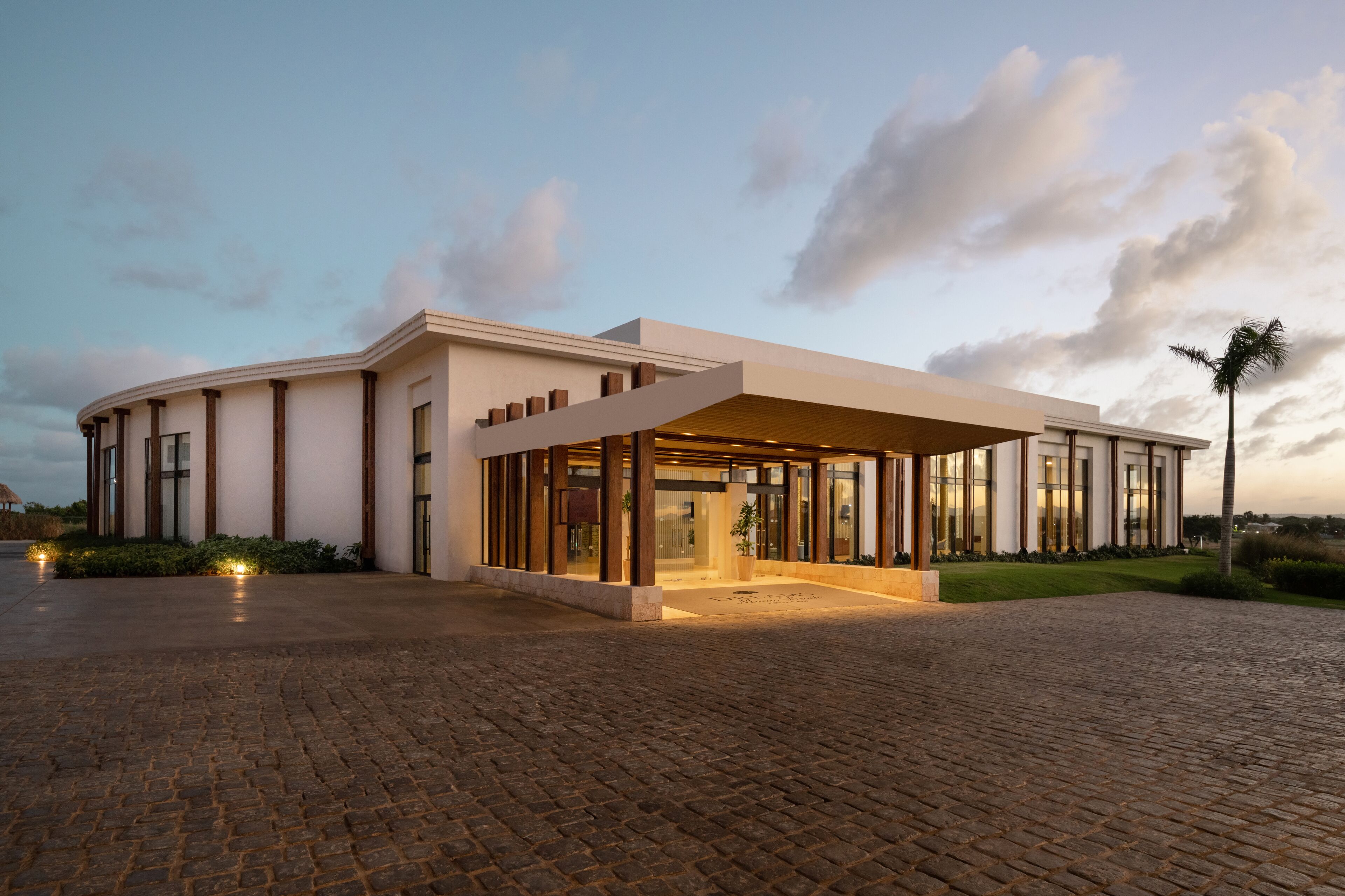 A modern building with a curved facade, large glass windows, and a covered entrance area.