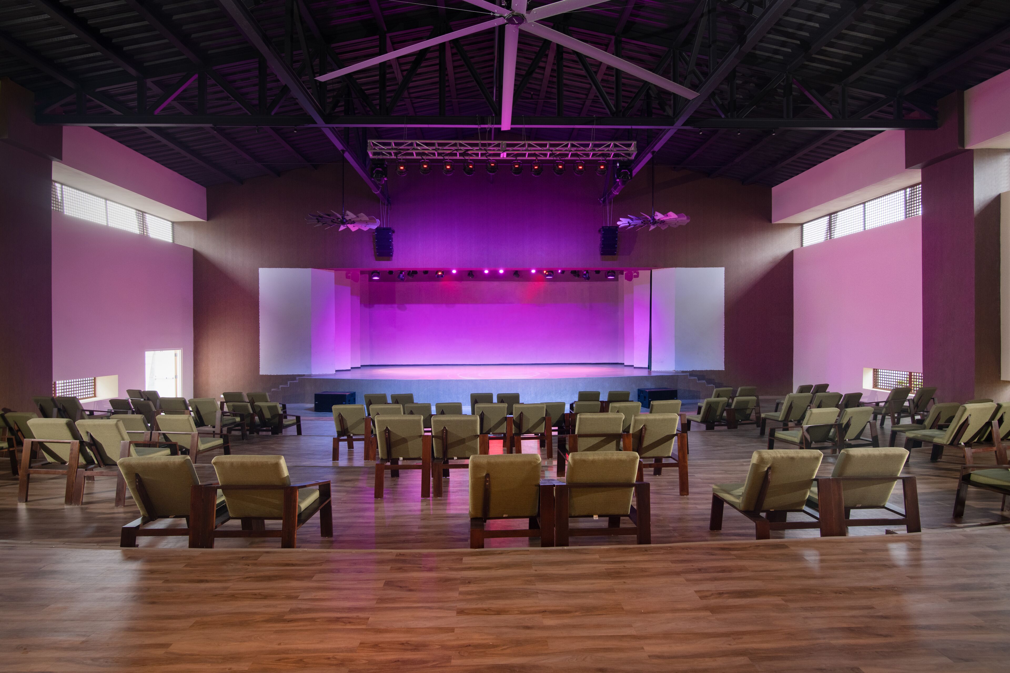 A spacious hall with rows of chairs facing a stage with a purple backdrop.