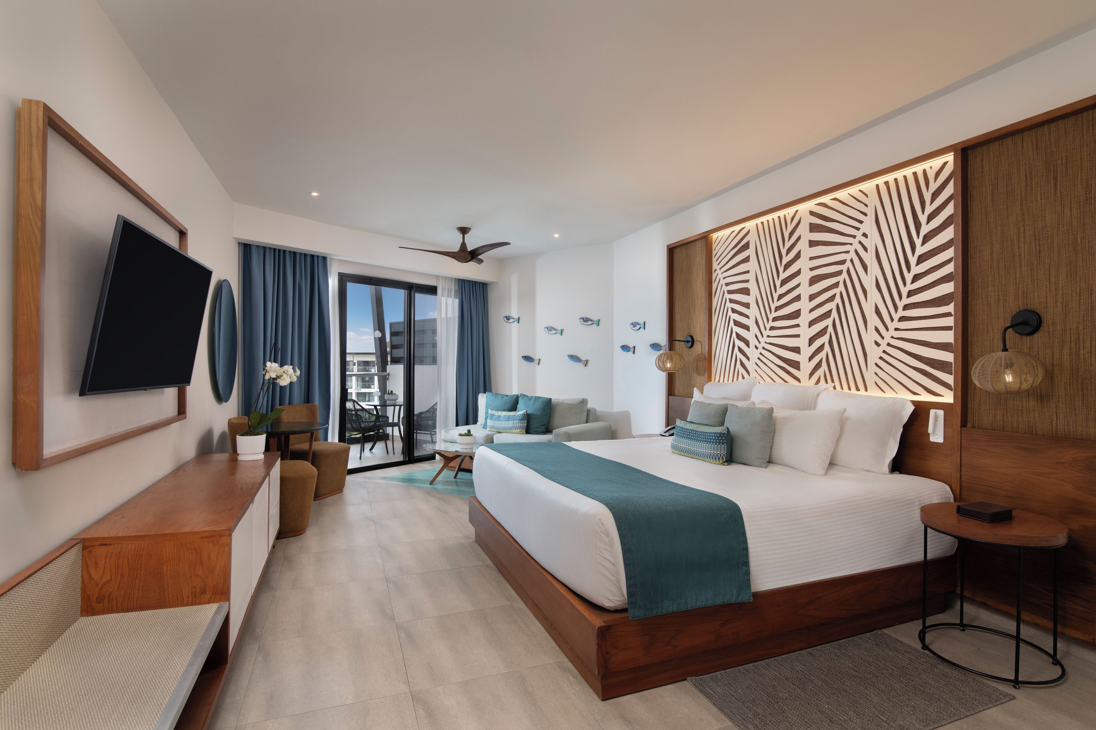 Una habitación de hotel moderna con una cama grande, un televisor de pantalla plana, un cabecero de madera y un balcón con vistas.