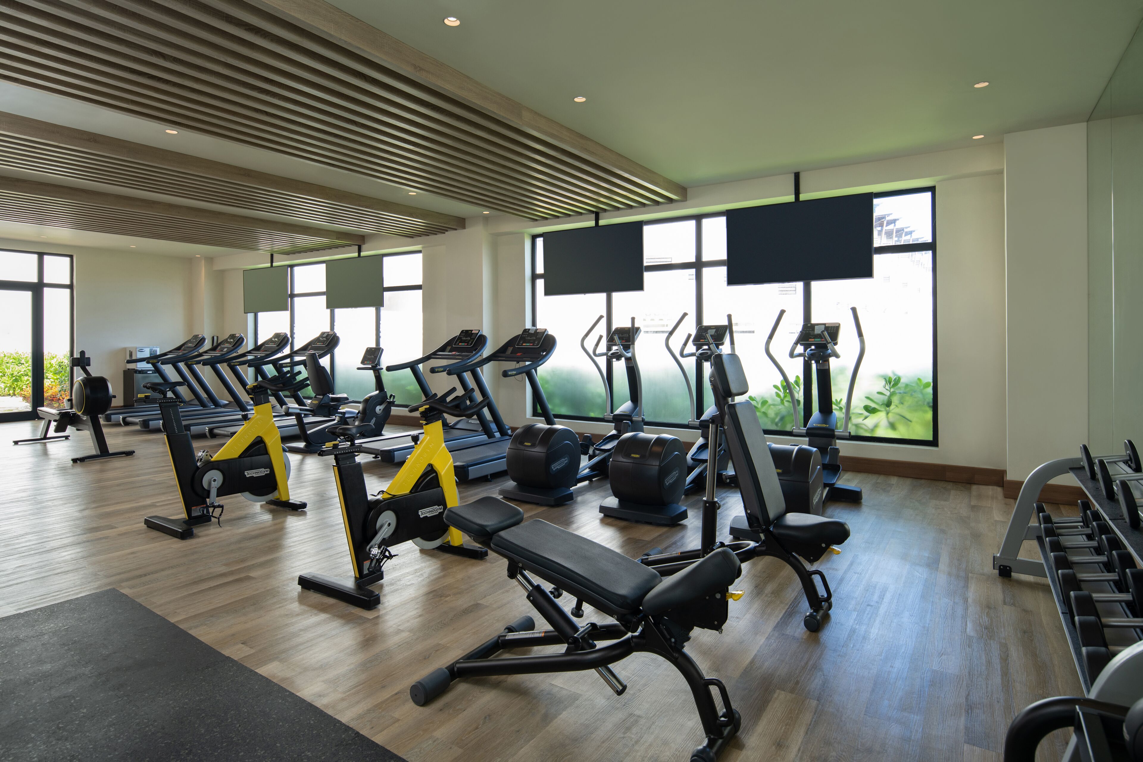 Un gimnasio moderno con cintas de correr, bicicletas estáticas y máquinas de pesas.