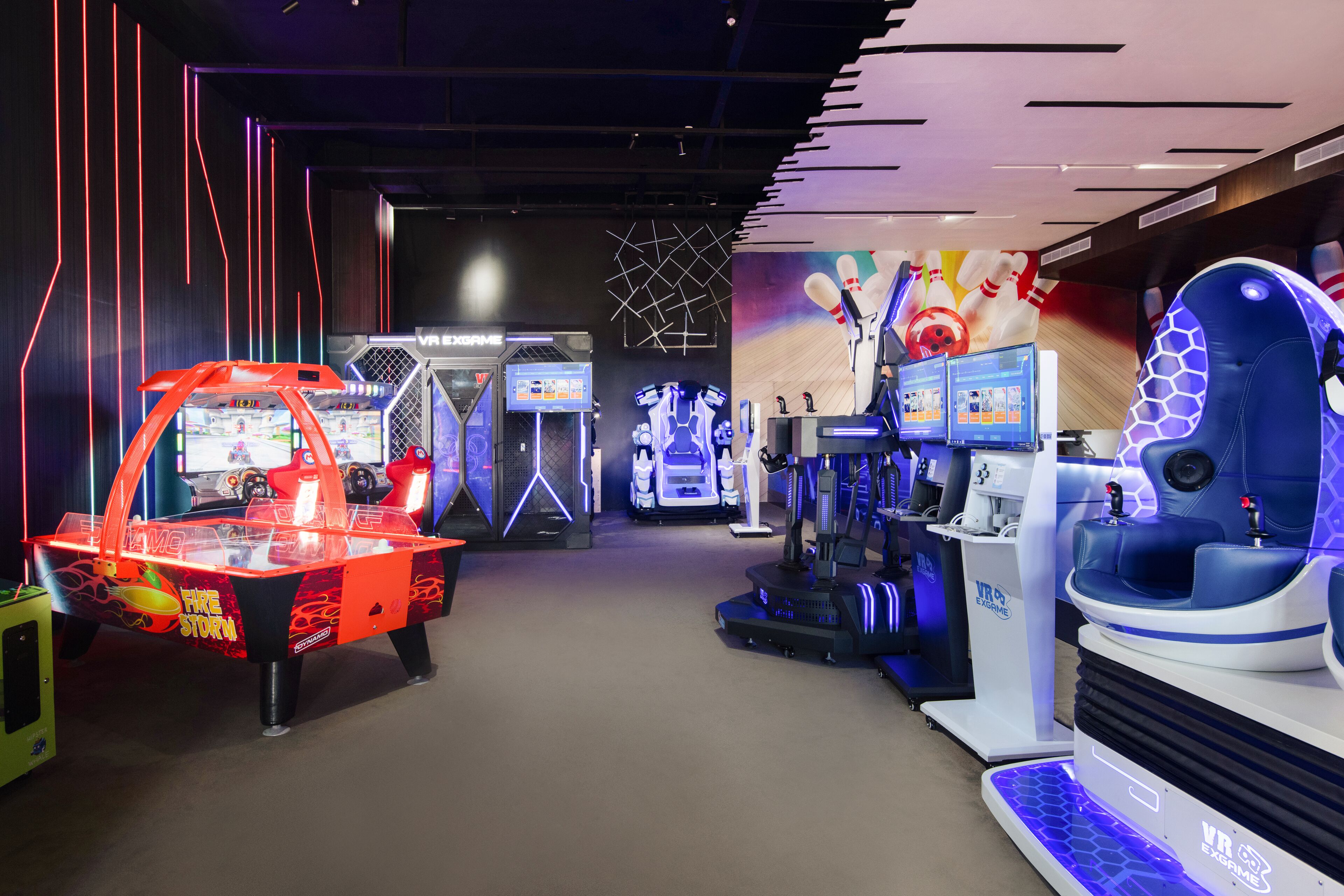 Un espace de divertissement intérieur comprenant divers jeux, notamment une station de jeux en réalité virtuelle et un simulateur de bowling.