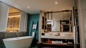 Une salle de bain moderne avec une baignoire sur pieds, un meuble-lavabo doté d’un grand miroir et un espace douche.