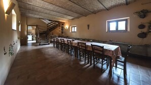 Una larga mesa de comedor con sillas, una escalera y un ventanal.