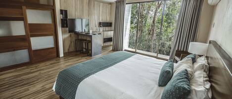 A hotel room with a large bed, a desk with a chair, a television, and a window with curtains.