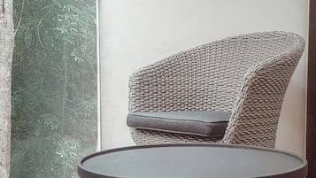 A wicker chair with a cushion and two round tables with wooden legs.