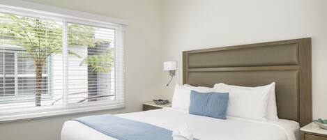 A hotel room with a bed, a nightstand, a lamp, and a ceiling fan.