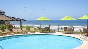 A pool area with lounge chairs and umbrellas, overlooking the ocean. - WCH at Wave Crest Resort (Del Mar)