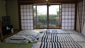 A traditional Japanese room with tatami flooring, a sliding door with shoji screens, and a bed with striped bedding. - ROSENCAT (Sado)