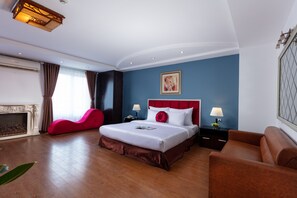 A hotel room with a large bed, a red sofa, a brown armchair, a fireplace, and a blue accent wall. - Hanoi Amore Hotel & Travel (Hanoi)