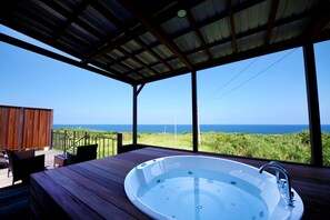 A hot tub on a wooden deck with a view of the ocean. - isola villa kouri (Nakijin)