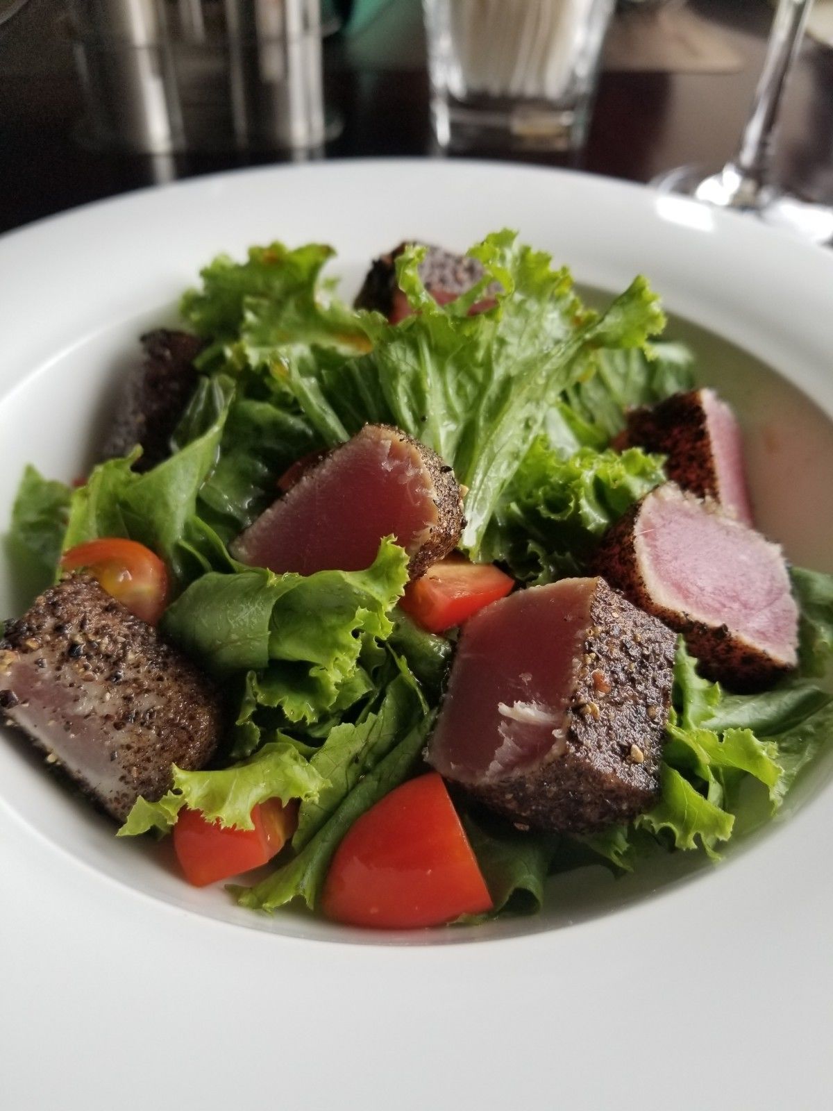 A plate of food with a salad, including lettuce, tomatoes, and slices of meat.