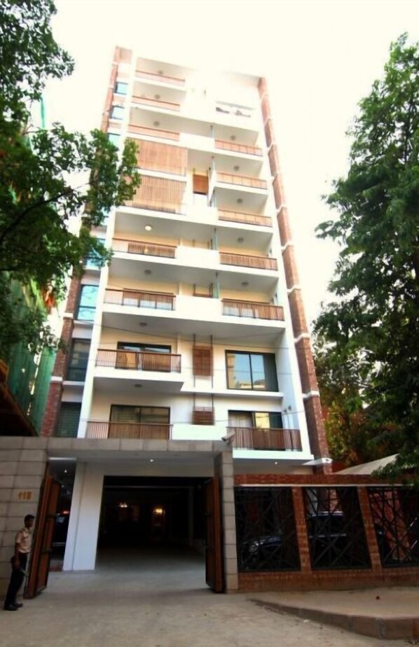 Un edificio de varios pisos con balcones, una entrada a nivel de calle y una persona parada cerca de la entrada.
