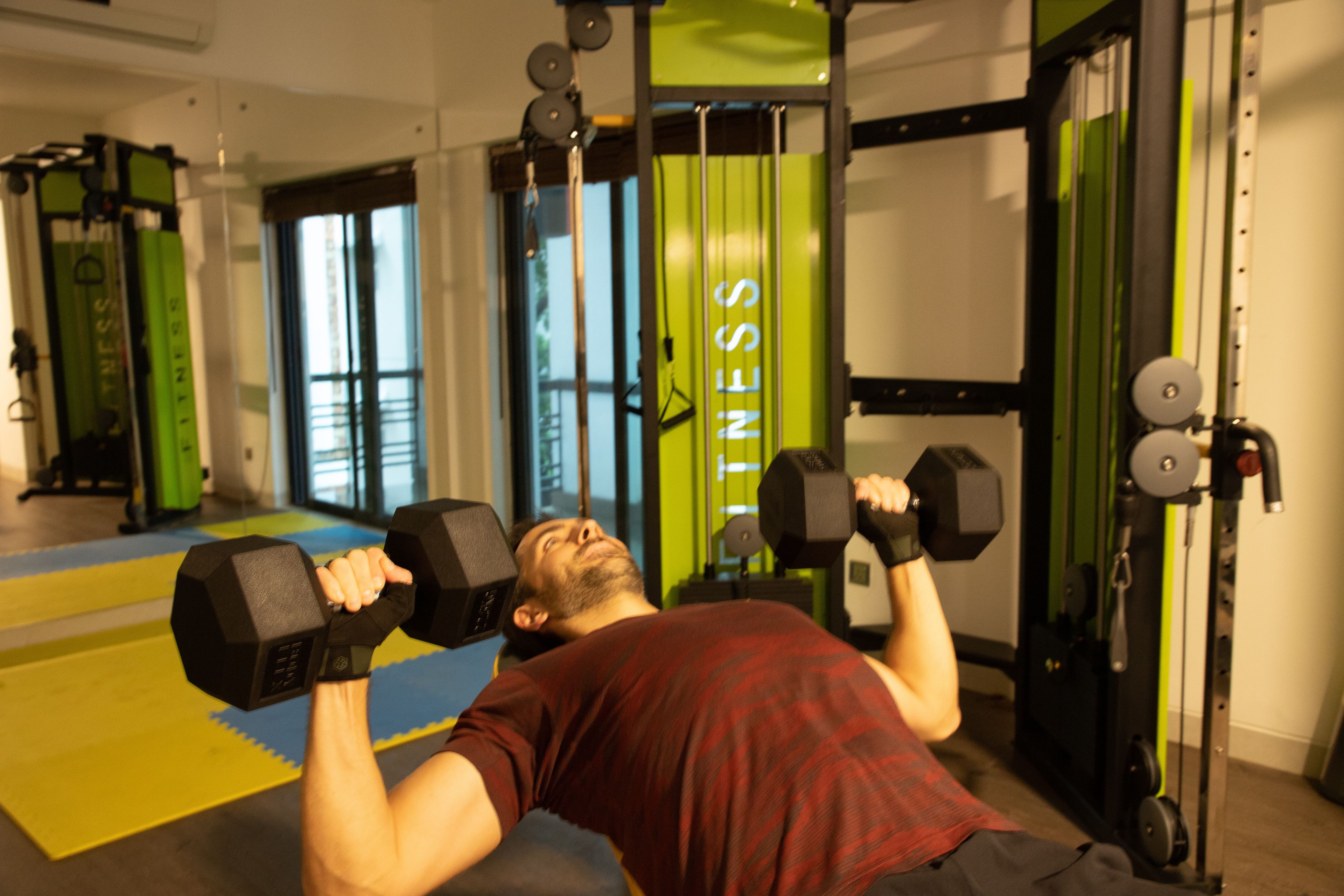 A gym with exercise equipment and a person performing a bicep curl.