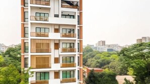 A multi-story residential building with balconies, surrounded by greenery.