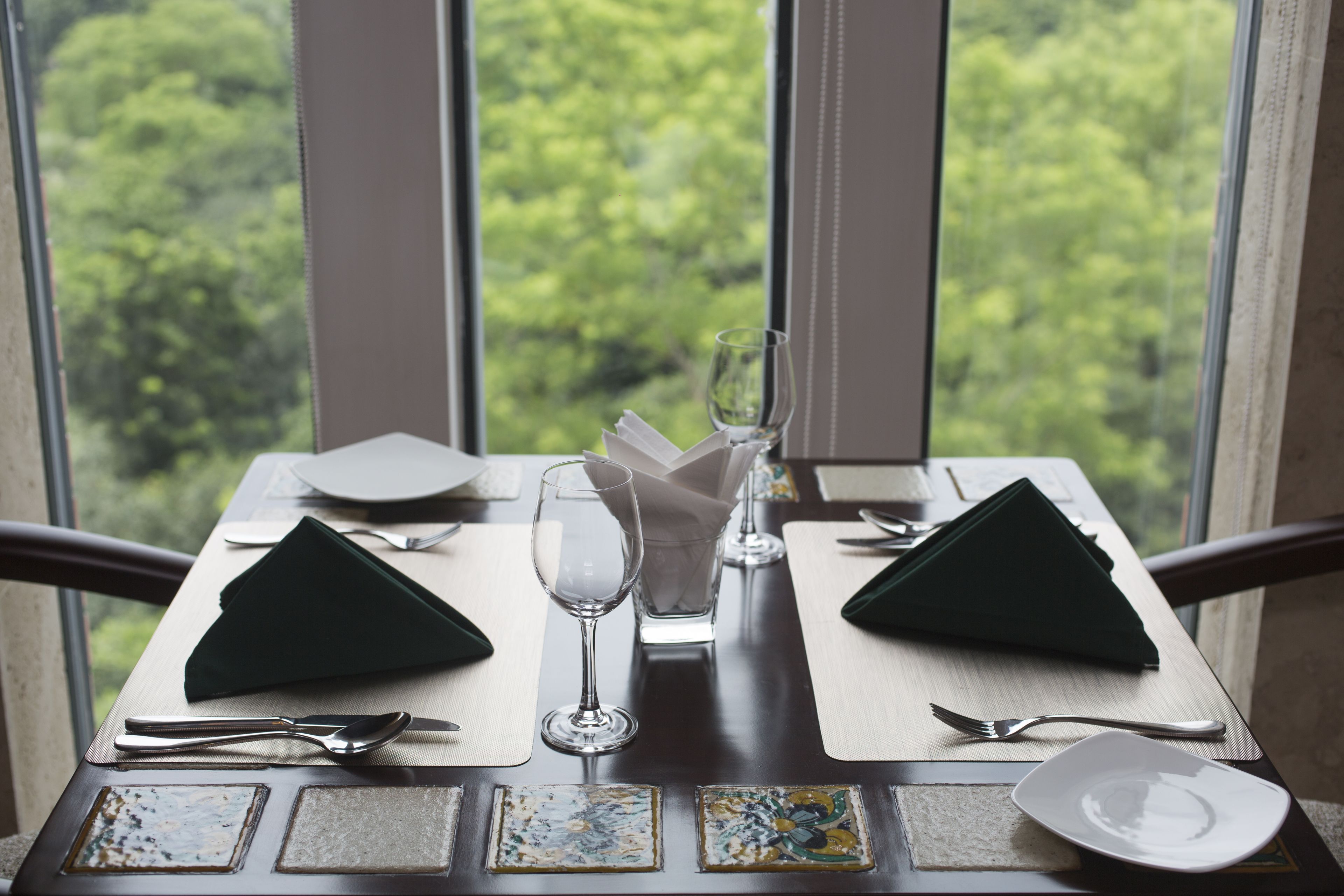 A dining table set with a green napkin, a wine glass, and cutlery.