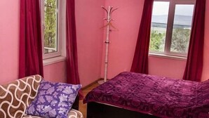 A room with pink walls, a bed with a purple bedspread, a sofa with a patterned cushion, and a wooden floor. - Amiran`s Lake (Tbilisi)