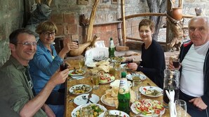 A group of people dining at a rustic outdoor table with various dishes and drinks. - Amiran`s Lake (Tbilisi)