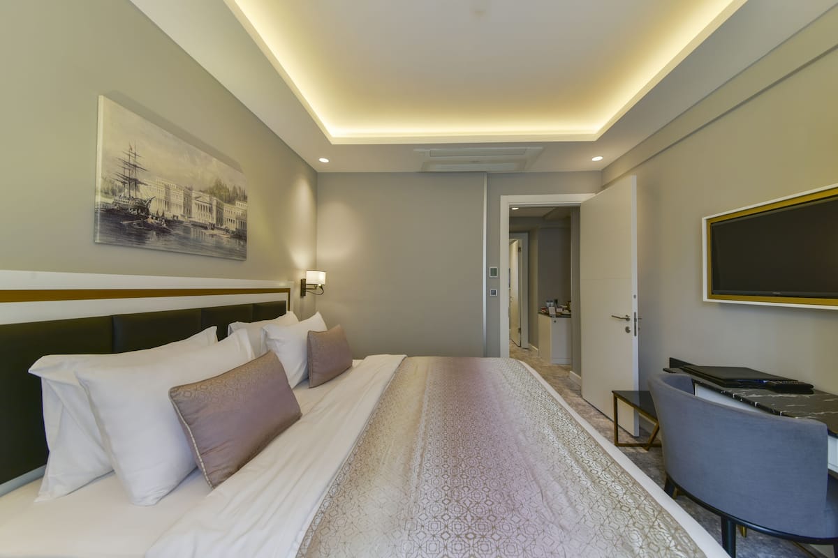 Une chambre d’hôtel avec un grand lit, une télévision et un tableau au mur.