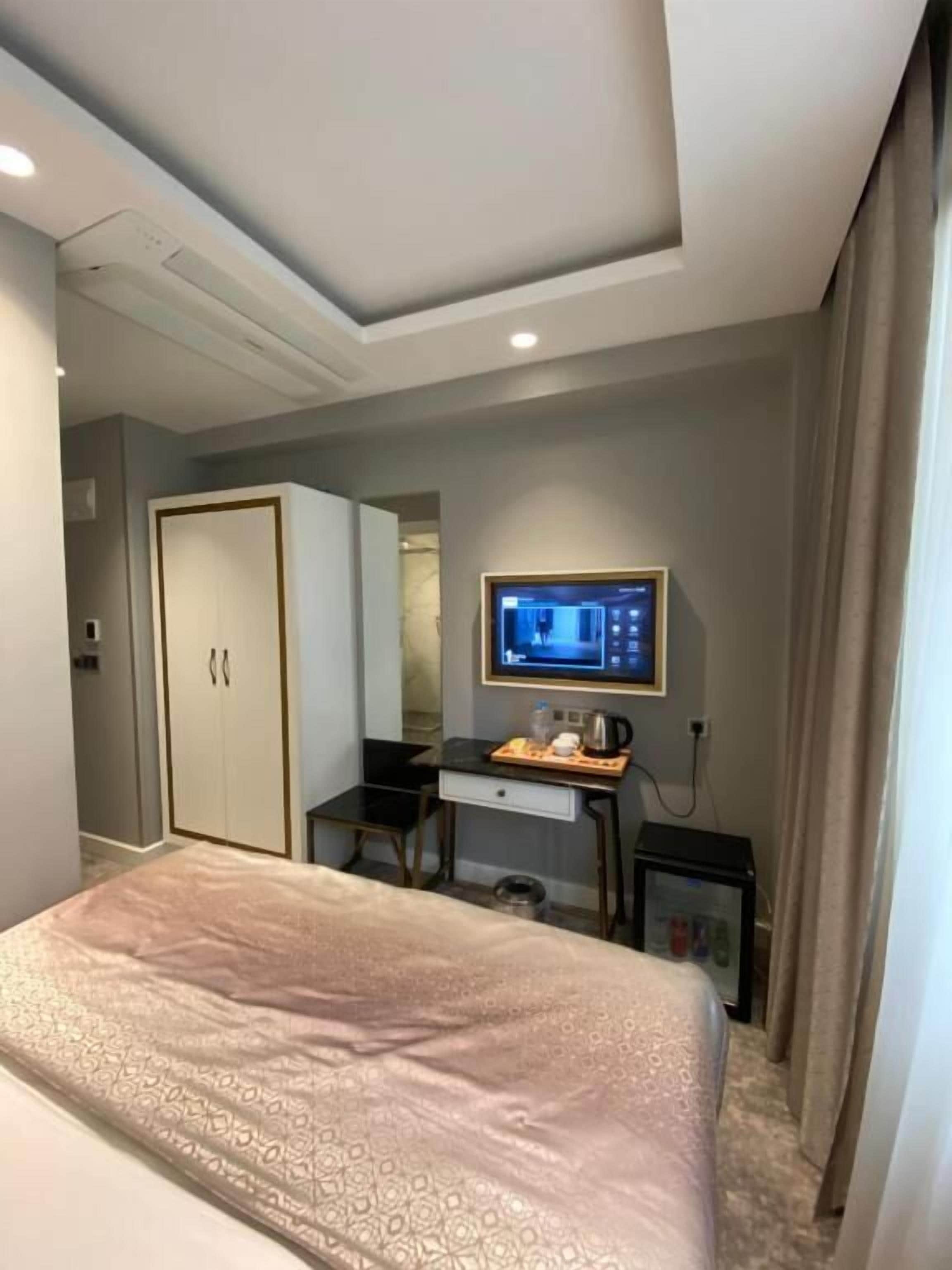 Una camera d'albergo con un letto, una scrivania con un computer, una televisione e un armadio.