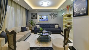 Una sala de estar moderna con un sofá, sillones, una mesa de centro y una televisión.