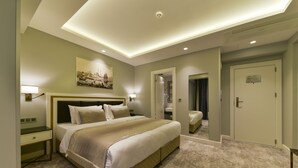 Una habitación de hotel con una cama grande, mesitas de noche, un espejo y una puerta.