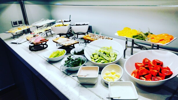 Un bufé con diversos alimentos, entre ellos verduras, frutas y carnes.