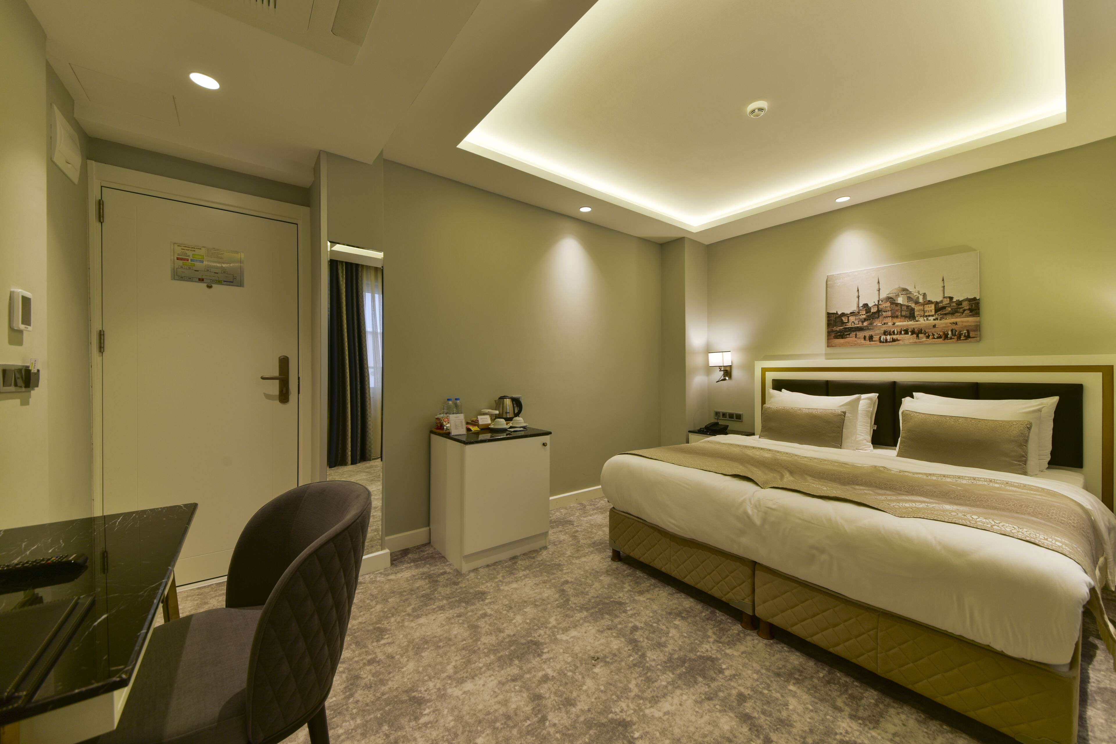 Ein Hotelzimmer mit einem Bett, einem Schreibtisch, einem Sessel, einem Nachttisch und einer Wandlampe.
