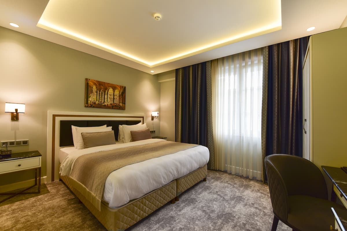 Une chambre d’hôtel avec un grand lit, un bureau et une chaise.