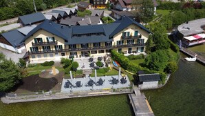 Un hotel frente al lago con un muelle, zona de estar al aire libre y un bote.