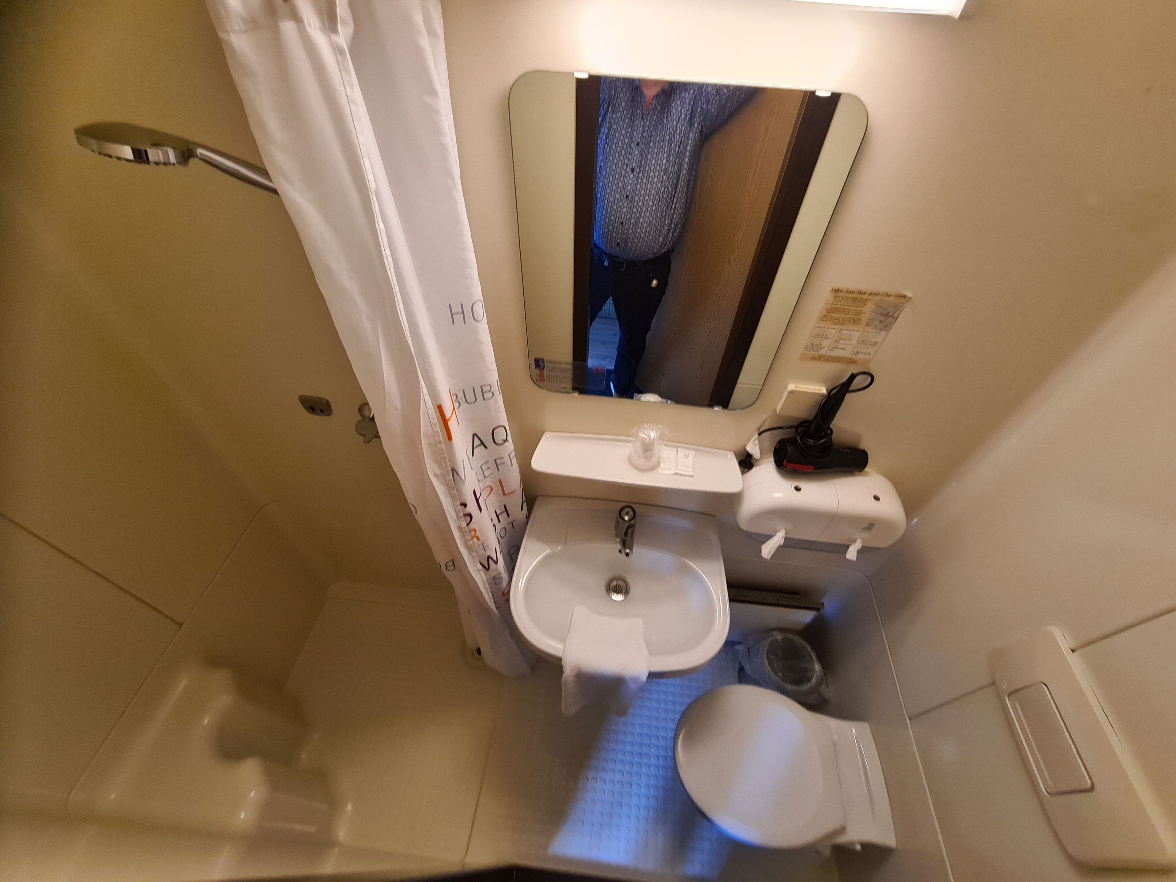 Un baño pequeño y funcional con inodoro, lavamanos y cortina de ducha.
