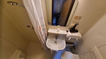 Un baño pequeño y funcional con inodoro, lavamanos y cortina de ducha.