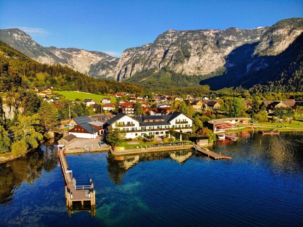 Un pueblo a orillas del lago con casas, un muelle y montañas al fondo.
