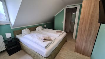 A bedroom with two beds, a nightstand, a lamp, and a view of the bathroom.