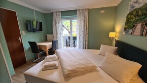 Habitación de hotel con una cama grande, un escritorio, una silla, un televisor y vistas al exterior.