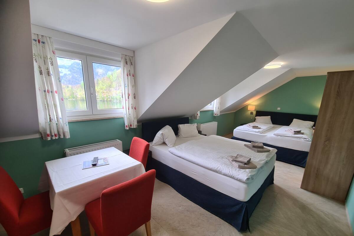 A room with two beds, a table, and red chairs.