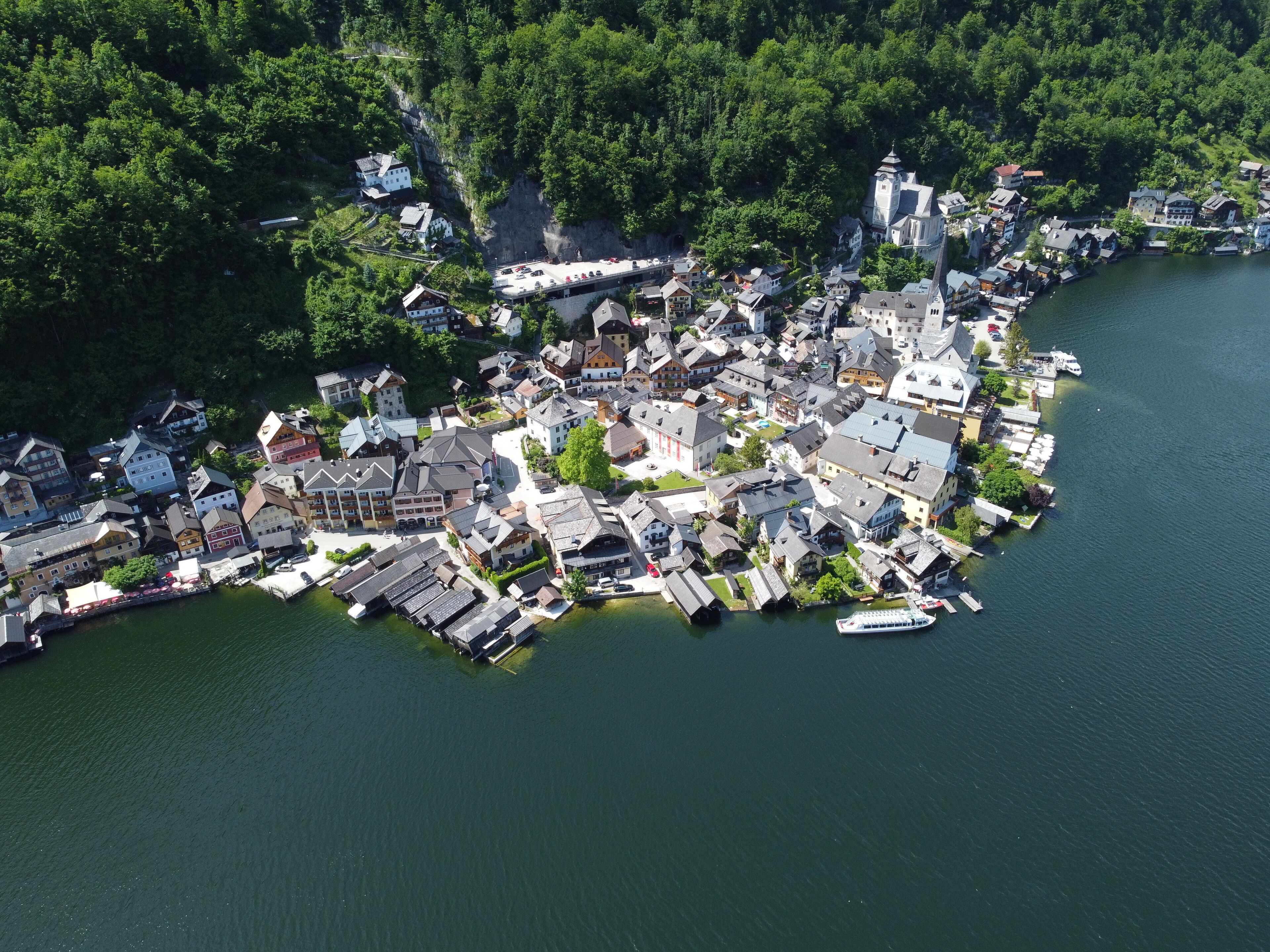 An aerial view of a lakeside village with traditional architecture, docks, and boats.