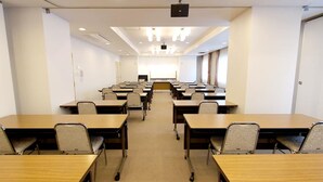 A conference room with rows of tables and chairs, a projector screen, and a whiteboard at the front. - Takamatsu City Hotel (Takamatsu)