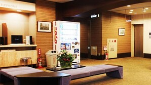 A reception area with a reception desk, a computer, a telephone, a fire extinguisher, and a bench. - Takamatsu City Hotel (Takamatsu)