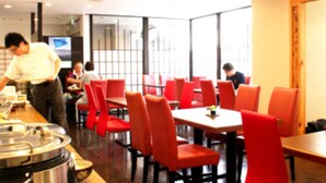A restaurant interior with red chairs and tables, a counter with a chef, and a large window. - Takamatsu City Hotel (Takamatsu)