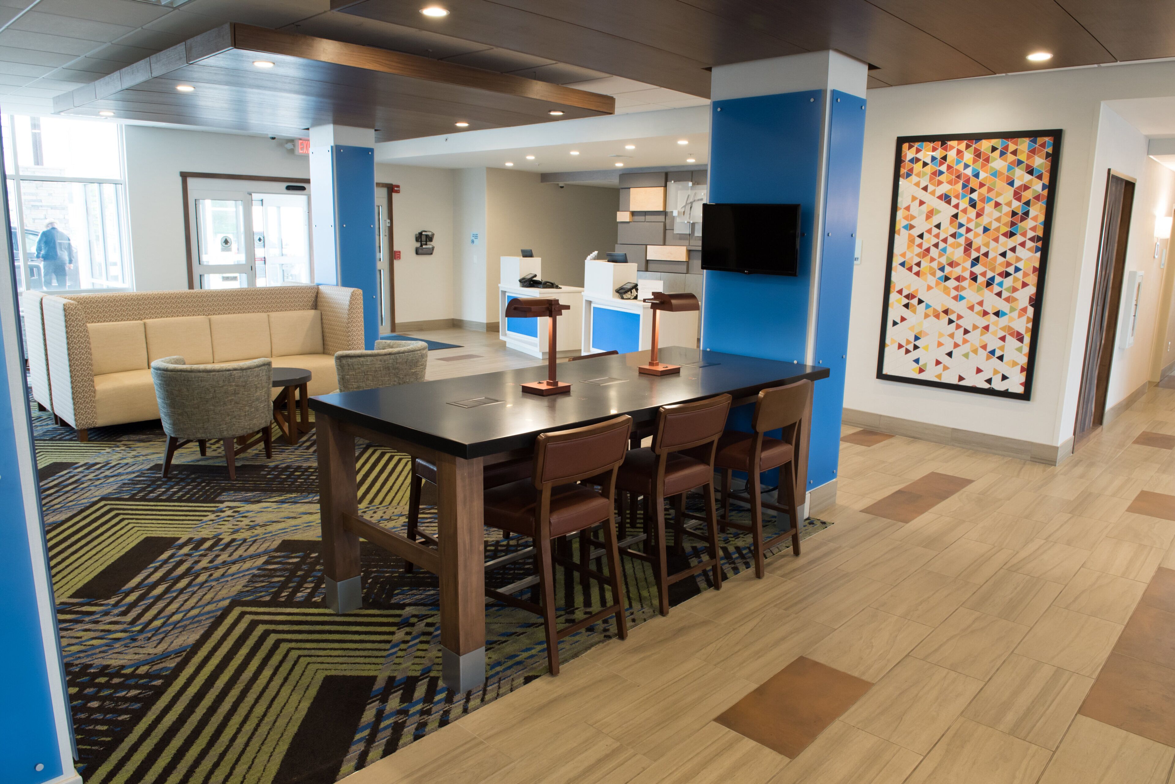 Eine moderne Hotellobby mit einer Rezeption, einer Sitzecke und einem großen abstrakten Gemälde.