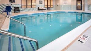 Une piscine équipée d’un dispositif d’élévation pour faciliter l’accès, un espace de détente avec des chaises, et un panneau indiquant le nombre maximal de baigneurs autorisé, soit 10 personnes.