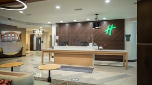 A modern hotel lobby with a reception desk, seating area, and a large wall-mounted sign. - Holiday Inn St. Louis - Creve Coeur by IHG (St. Louis)