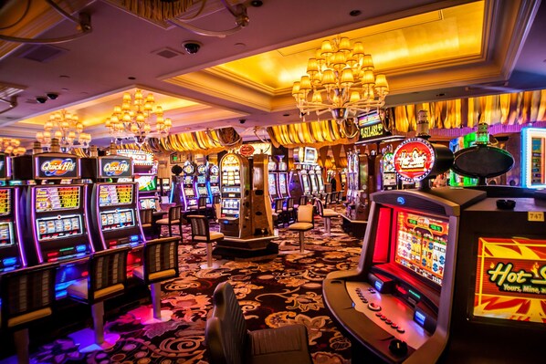 A casino floor with slot machines, chandeliers, and a carpeted floor. - Holiday Inn St. Louis - Creve Coeur by IHG (St. Louis)
