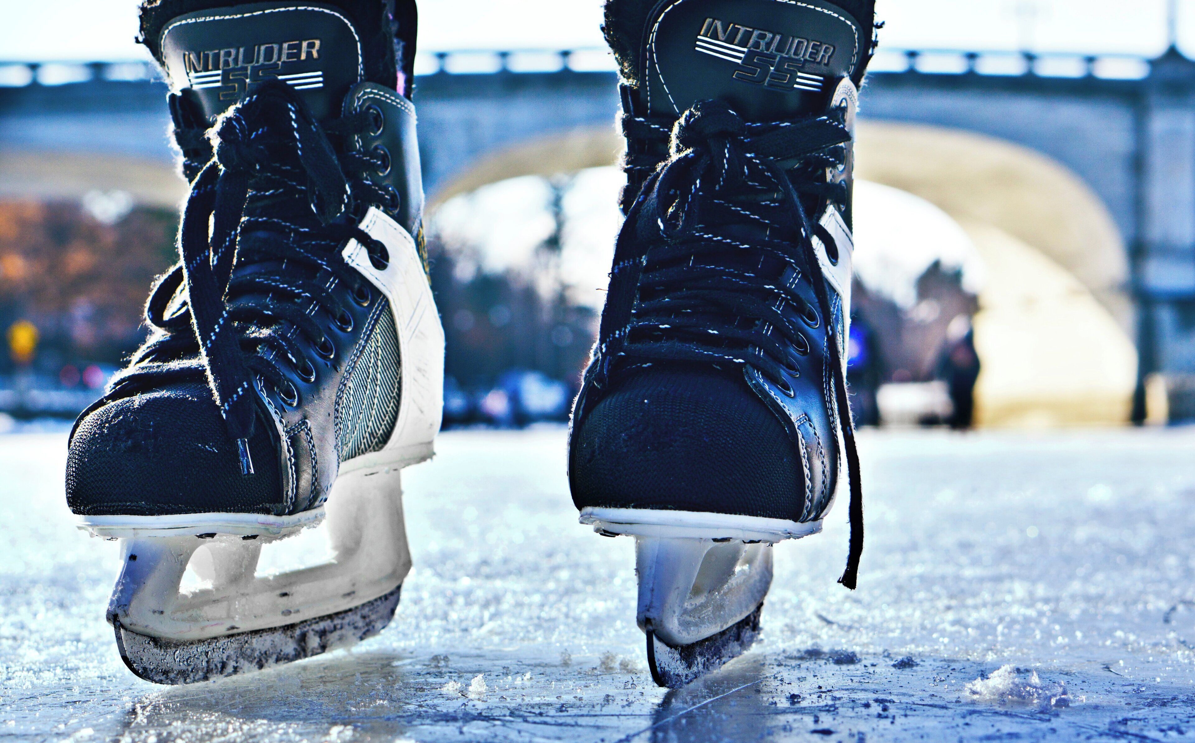 Un par de patines de hielo con señales de uso y un puente al fondo.