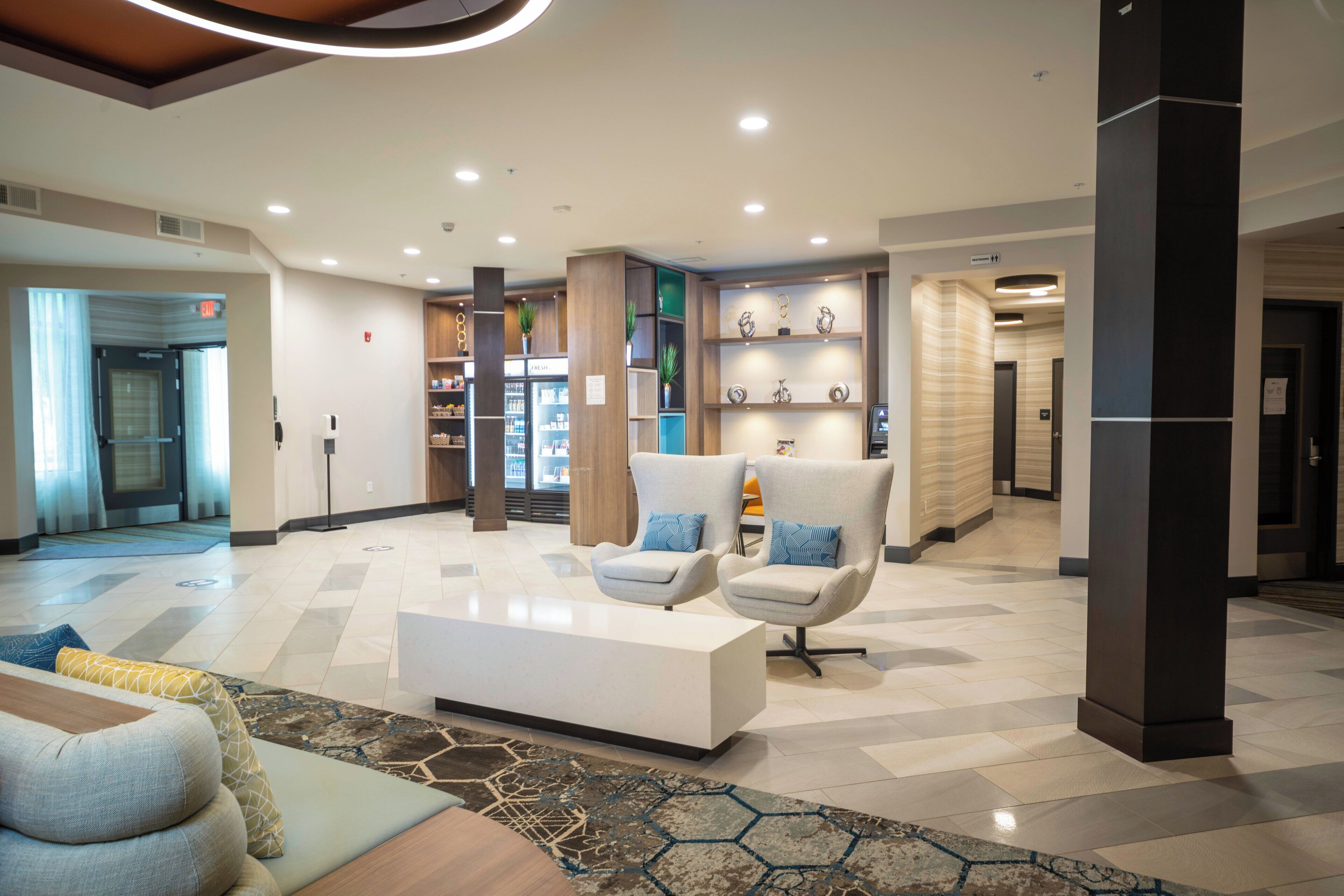 A modern lobby with a reception desk, seating area, and a refreshment bar.