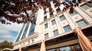 A building with classical architecture, large windows, and outdoor seating with umbrellas. - Mercure Timisoara (Timisoara)
